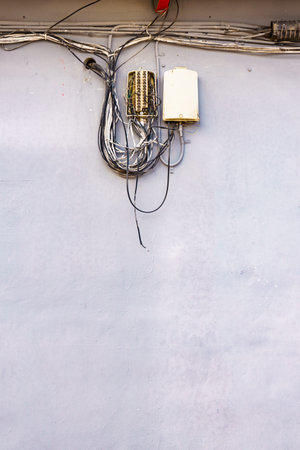 Cable power cords in tangled mess on building wall outdoorの写真素材
