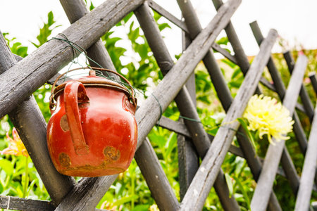 Old red pot hanging on country fence.