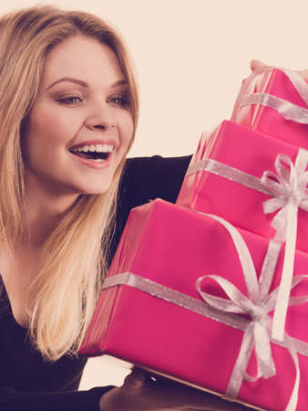 People celebrating xmas love and happiness concept. Cheerful blonde girl holding presents pile of pink gift boxes.の写真素材