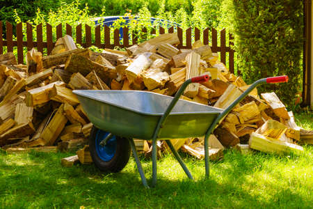 Stack of chopped firewood outside and wheelbarrow. Preparation for winter.の写真素材