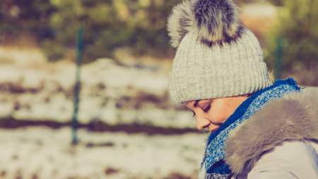 Pretty young woman wearing warm accessories during winter time. Female having grey beanie warm hat with pompons and blue scarf.の写真素材