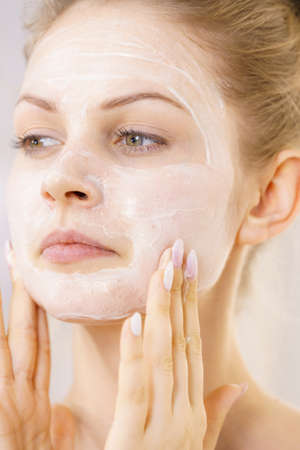 Young woman applying cream cosmetic, mask moisturizing to her face. Beauty treatment. Skincare.の写真素材