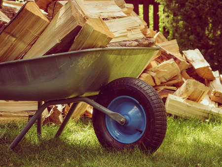 Stack of chopped firewood outside and wheelbarrow. Preparation for winter.の写真素材