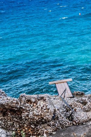 Small makeshift wooden jetty pier port for boats and yachts, blue calm water near seaside.
