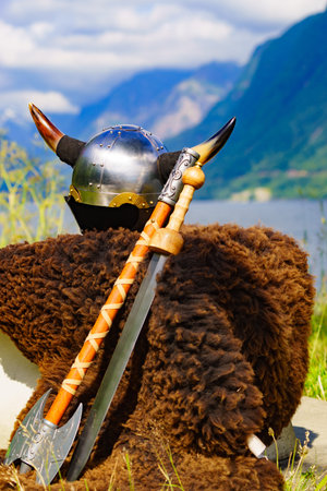 Viking helmet with weapons on fjord shore in Norway. Tourism and traveling concept