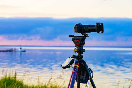 Professional camera on tripod taking picture film video of sea coastal landscape.の写真素材