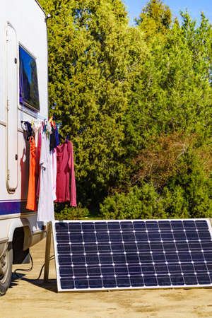 Laundry and portable solar photovoltaic panel, charging battery at camper car rv. Camping on nature.の写真素材