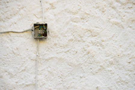 Electric box outdoors on white building wall.の写真素材