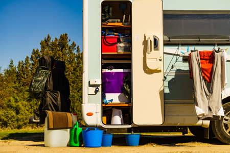 Doing laundry outdoors at caravan. Buckets outside and washing machine working inside of camper storage.の写真素材