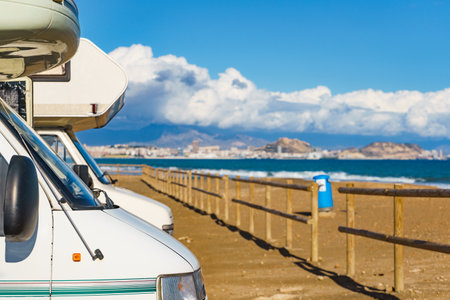 Caravan on mediterranean coast, Alicante city in the distance, Costa Blanca Spain. Wild camping on beach. Holidays and traveling in motor home.の写真素材