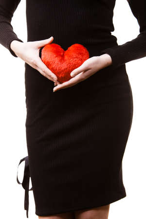 Young woman expecting baby. Pregnant female holding small heart shaped pillow on her stomach.の写真素材