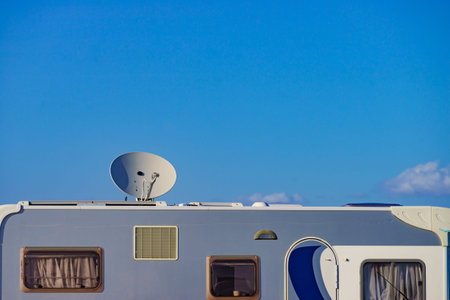 Satellite dish on roof of camper car against blue sky. TV connection. Travel holidays in mobile...