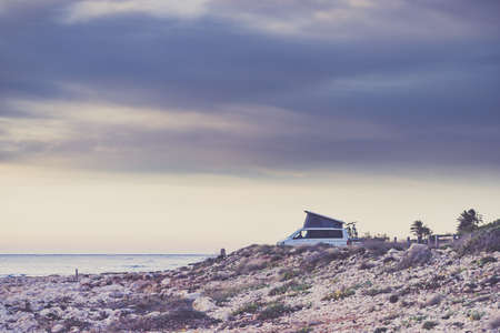 Van camper with roof top tent camping on mediterranean coast. Holidays and travel in mobile home. Van life.の写真素材