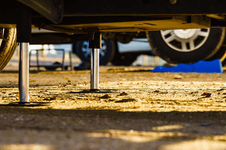 Auto leveling system for camper. Hydraulic steady leg in use. Blue leveler ramp chock block for rv in background.の写真素材