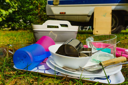 Dirty dishes outdoor against camper vehicle. Washing up on fresh air. Adventure, camping on nature, dishwashing outside.の写真素材