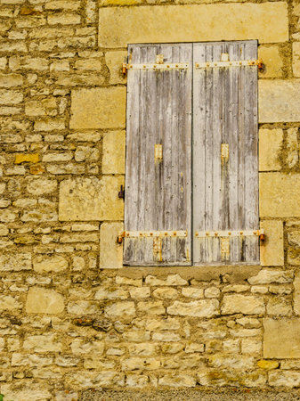 Traditional stone building with old wooden shutter window, France.