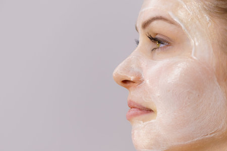 Young woman with cream cosmetic, mask moisture on her face. Beauty treatment. Skincare. Side view