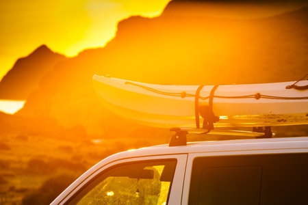 Car van with canoe on top roof against sunset sky. Active lifestyle, vanlife concept.の写真素材