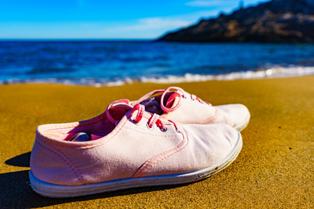 Female sneakers on sand beach. Walking on the seashore.の写真素材