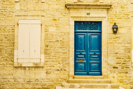Stone house facade with old wooden dark blue entrance door and shutters window. Architecture in France.の写真素材
