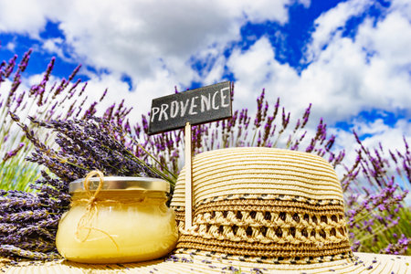 Summer hat, jar with honey and board with sign Provence against fresh lavender field. Attraction trip for french vacation.の写真素材
