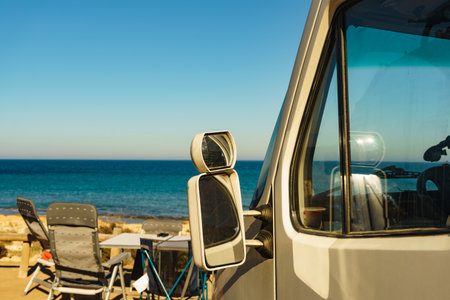 Camper car and tourist table with chairs on spanish sea coast. Camping on seaside. Holidays and travel.の写真素材