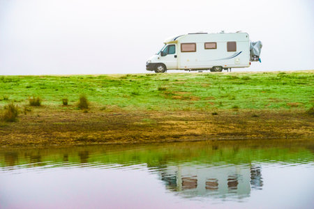 Camping on nature. Camper vehicle at lake shore, foggy weather. Povoa e Meadas Dam in Castelo de Vide, Alentejo Portugal. Travel in wintertime.の写真素材