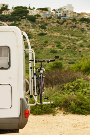 Camper, recreational vehicle with bicycle on back rack. Camping on nature, holidays and travel in...