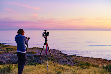 Tourist woman photographer with two cameras taking travel photo on nature at sunset time.の写真素材