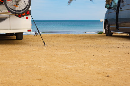 Camping on sea shore. Camper vehicle and fishing rod on beach, mediterranean coast in Spain.の写真素材
