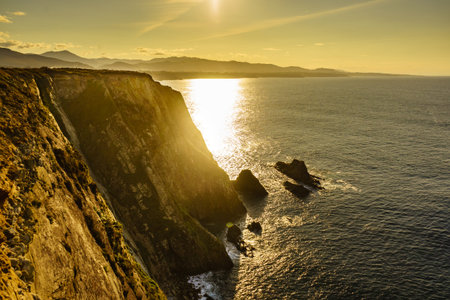 Sunset over rocky cliffs at Asturias coast in north Spain. View from Faro de Cabo Busto. Tourist...