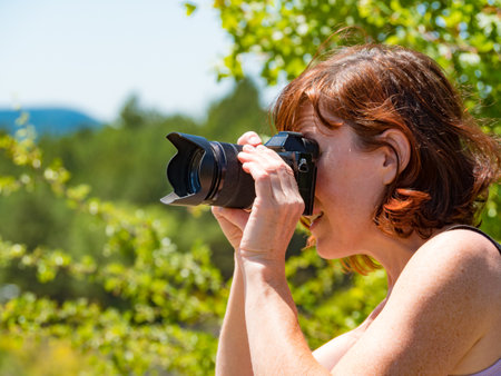 Tourist mature woman take travel picture from green landscape.の写真素材