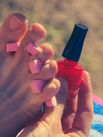 Woman waiting untill her feet nails dry on sun during summertime vacations. Female having toes...