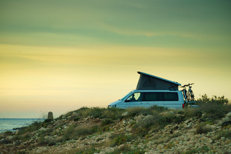 Van camper with roof top tent camping on mediterranean coast. Holidays and travel in mobile home. van life.の写真素材