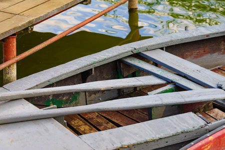 Old wooden fishing boat with paddles on lake shore. Summer activities.の写真素材