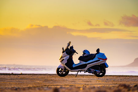 Scooter motorbike on beach sea shore at sunrise. Touring in nature.の写真素材