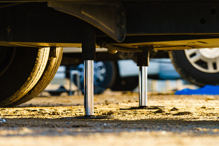Auto leveling system for camper. Hydraulic steady leg in use. Blue leveler ramp chock block for rv in background.の写真素材