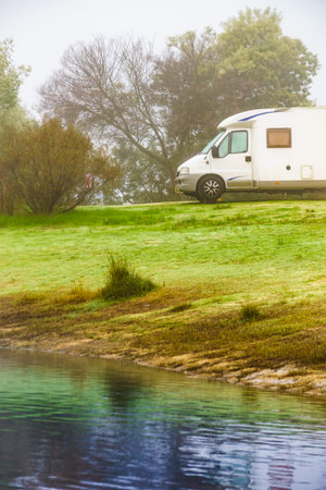 Camping on nature. Camper vehicle at lake shore, foggy weather. Povoa e Meadas Dam in Castelo de Vide, Alentejo Portugal. Travel in wintertime.の写真素材