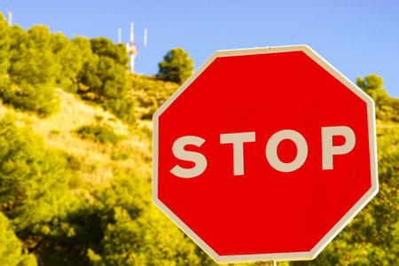 Traffic stop red sign by the road. Mountain nature in the background.