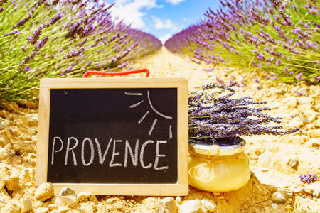 Jar with honey and board with sign Provence against fresh lavender field background. Attraction trip for French vacation.の写真素材