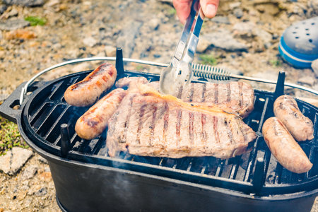 Meat and sausage on barbecue grill. Barbeque dinner outdoor, summer food.の写真素材