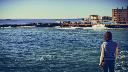 Tourist woman on spanish rocky coastline. Windy day. Torrevieja, province of Alicante.