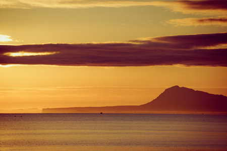 Sunrise over the sea. Montgo mountain massif silhouette on horizon. View from beach near Gandia, Valencia Spainの写真素材