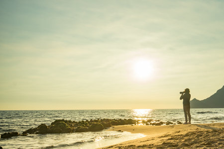 Tourist woman with camera taking travel picture on Monsul beach. Cabo de Gata Nijar Natural Park,...