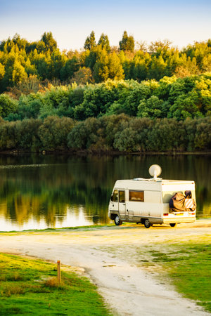 Caravan camping on lake shore. Satellite dish on roof of camper vehicle. TV connection. Travel holidays in motor home.の写真素材