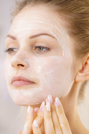 Young woman applying cream cosmetic, mask moisturizing to her face. beauty treatment. skincare.の写真素材