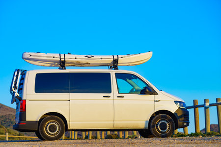 Car van with canoe on top roof against sky. Active lifestyle sports concept.の写真素材