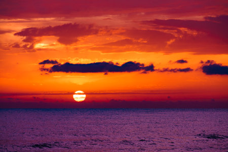 Sunrise over the sea. Burning sky with over water surface. Sun rising above the horizon. Morning seascape.の写真素材