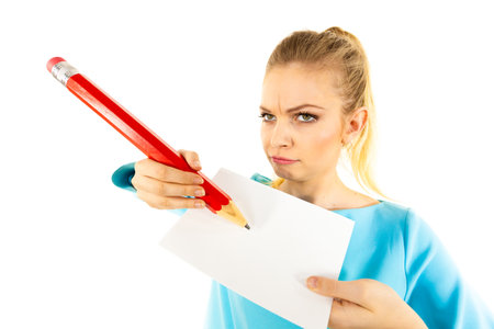 Teenage thinking woman writing some notes on piece of paper using big oversized pencil.の写真素材