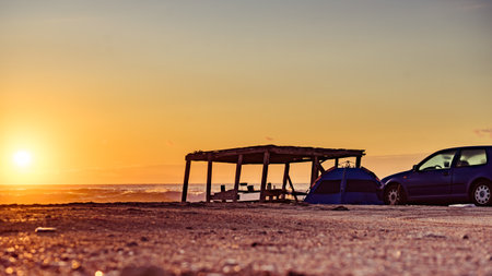 Wooden shelter and tent with car on beach in morning light.の写真素材